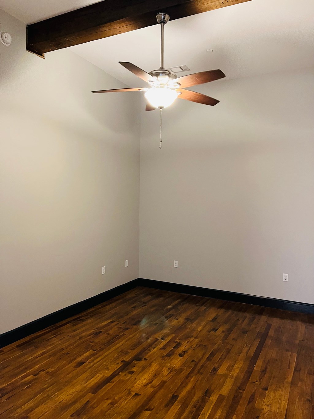 A room with a ceiling fan and wooden floors.