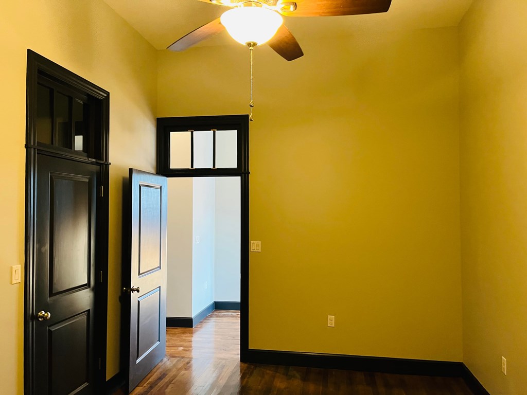A room with a ceiling fan and a door.