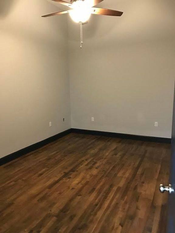A room with a ceiling fan and wooden flooring.