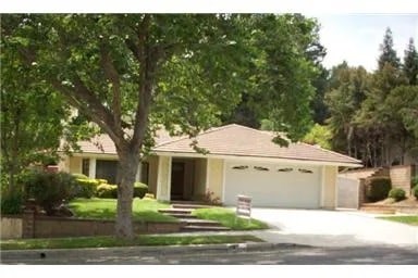 A house with a garage and a tree in front.