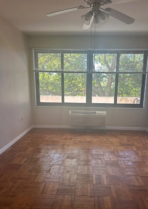 A room with a ceiling fan and a window with blinds.