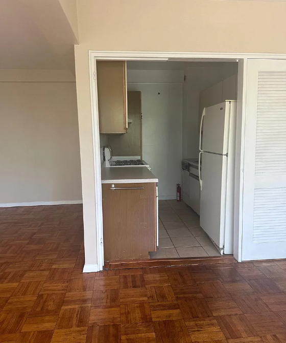 A kitchen with a white fridge and wooden floors.