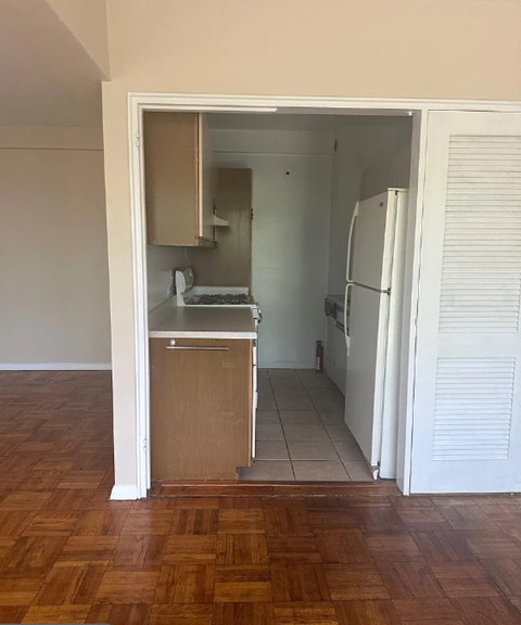 A kitchen with a refrigerator and a sink is visible through an open door.