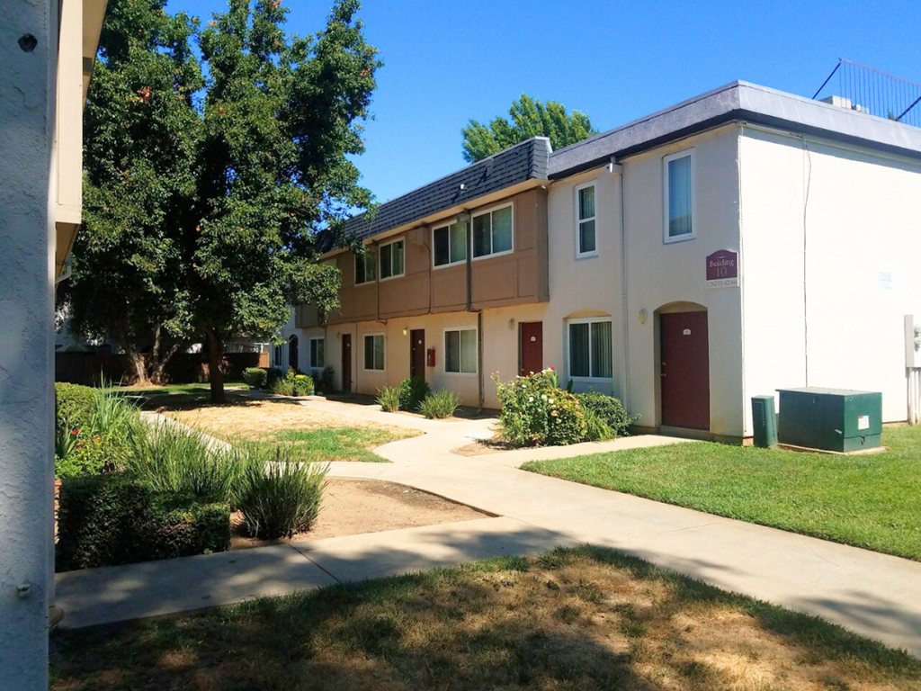 A building with a red door and a green trash can in front of it.