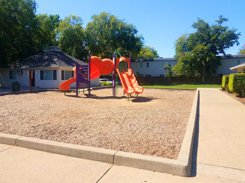 A playground with a red slide and orange climbing frame.
