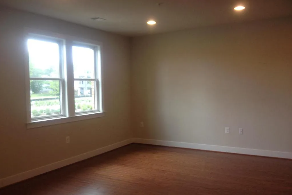 A room with brown floors and two windows.