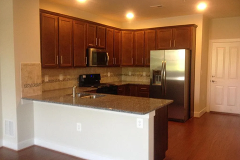 A kitchen with brown cabinets and a granite counter.
