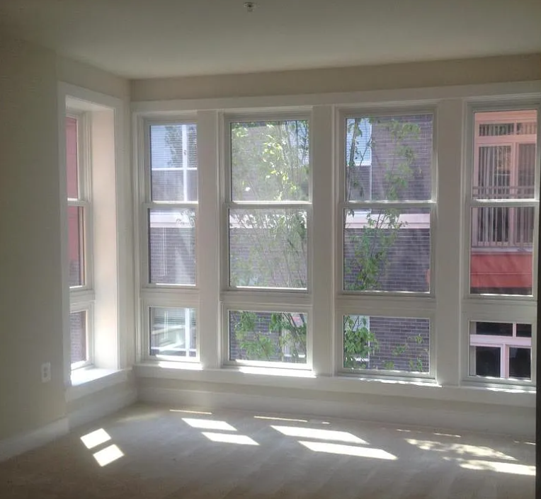 A sunny room with large windows and wooden floors.