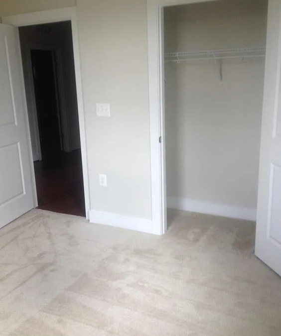 A room with a white door and a light switch on the wall.