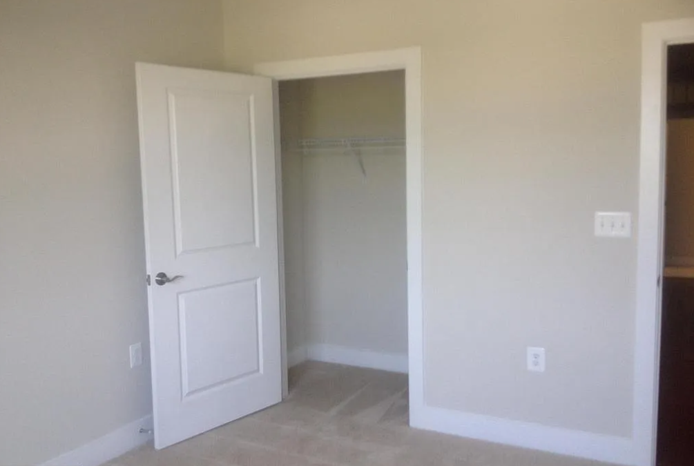 A white door is open to a room with a carpeted floor.