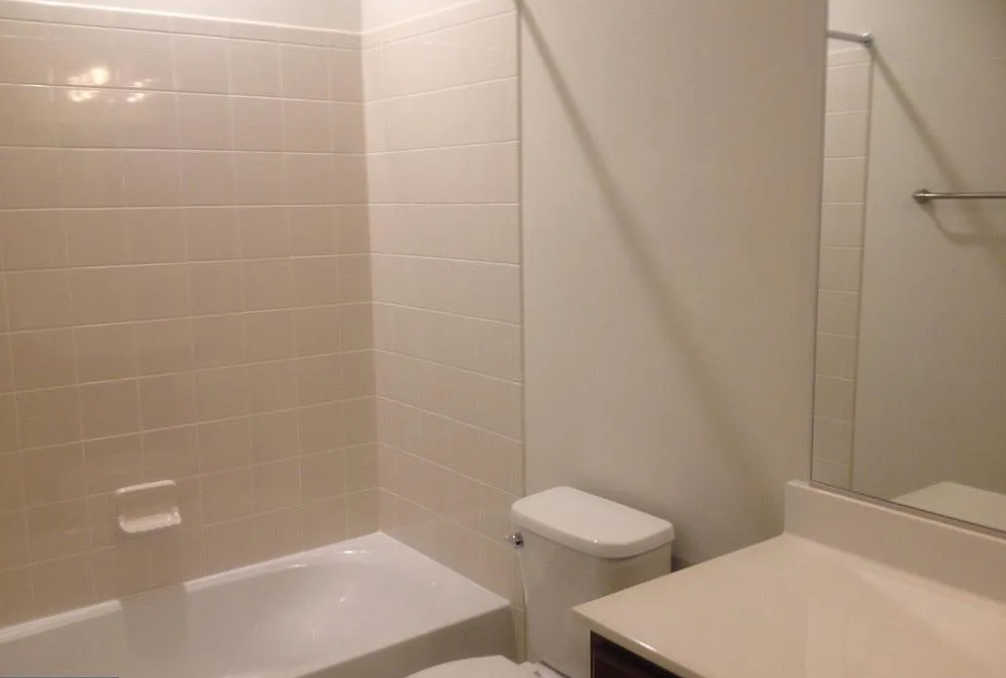 A white toilet sits next to a white bathtub in a bathroom.