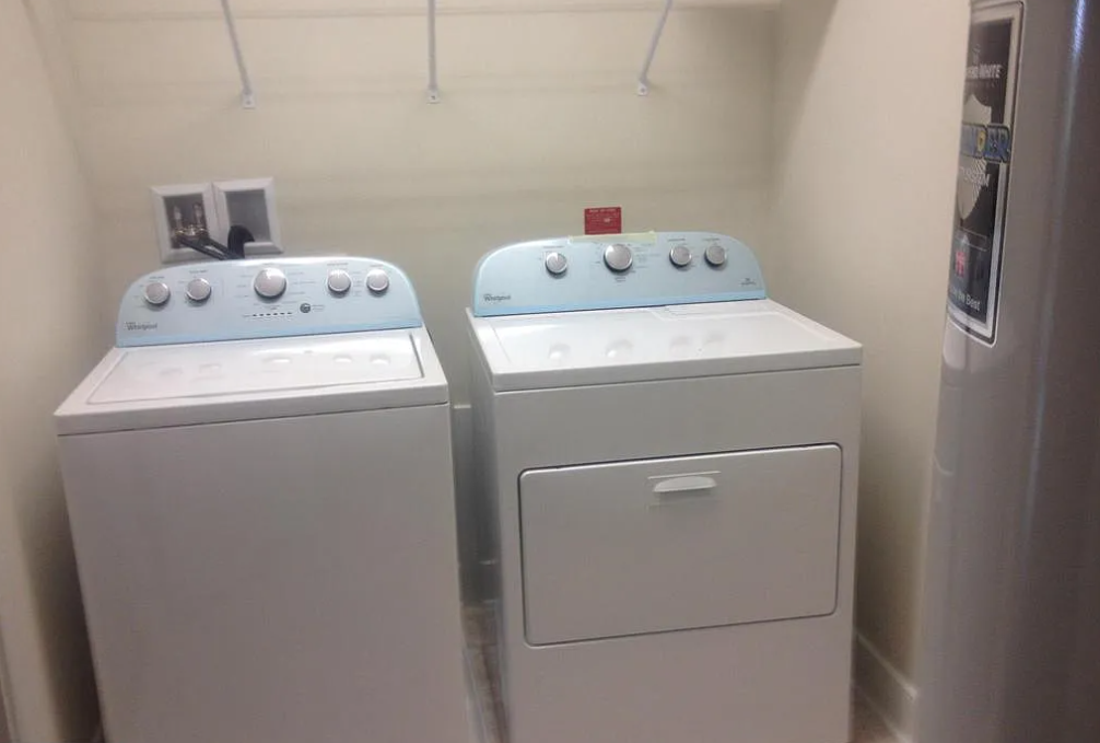 Two white washing machines in a laundry room.