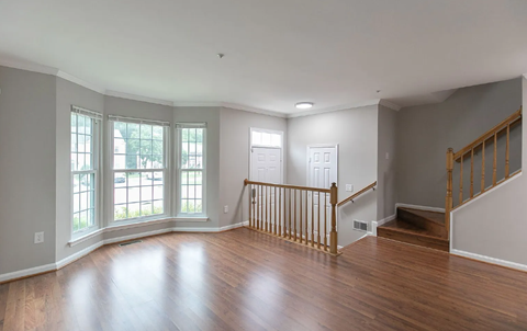 A spacious room with wooden floors and a staircase.
