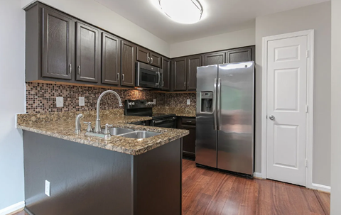A kitchen with dark brown cabinets and a granite countertop.