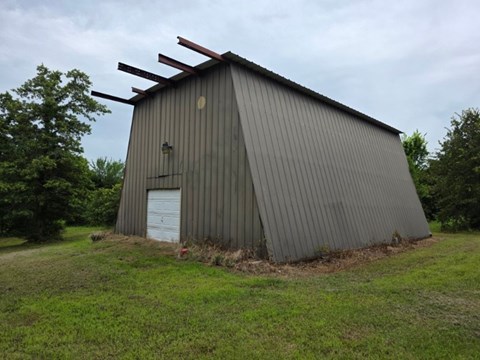 A large grey building with a white door and a metal roof.