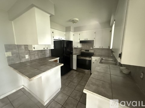 A kitchen with black appliances and white cabinets.