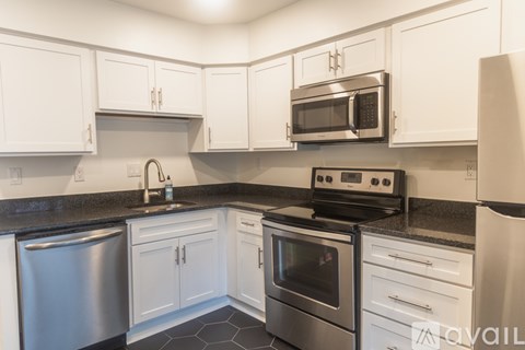 A kitchen with white cabinets and black countertops.