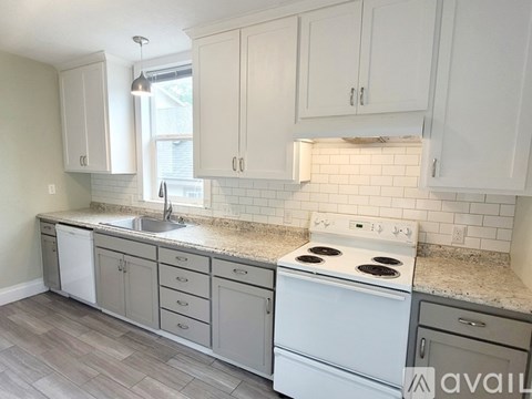 A kitchen with white cabinets and a white stove top oven.