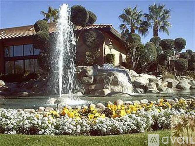 A fountain in a garden with a house in the background.
