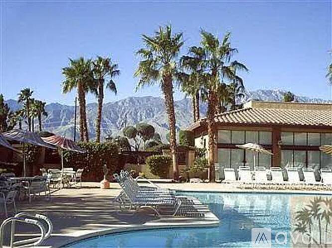 A pool surrounded by palm trees and lounge chairs.