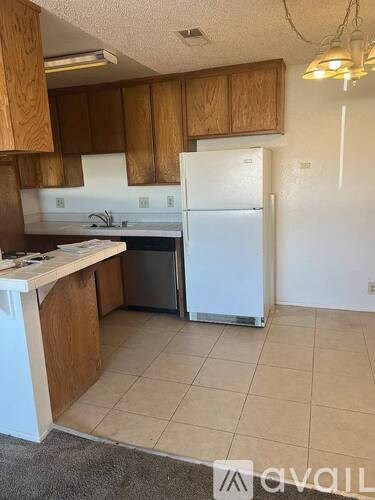 A kitchen with a white refrigerator and wooden cabinets.