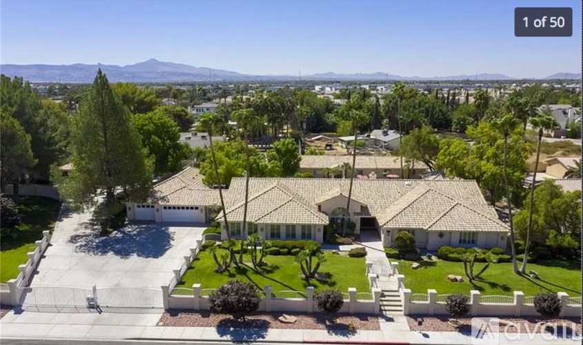 A large house with a driveway and a mountain in the background.