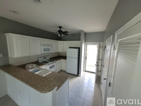 A kitchen with white cabinets and a countertop with a sink.