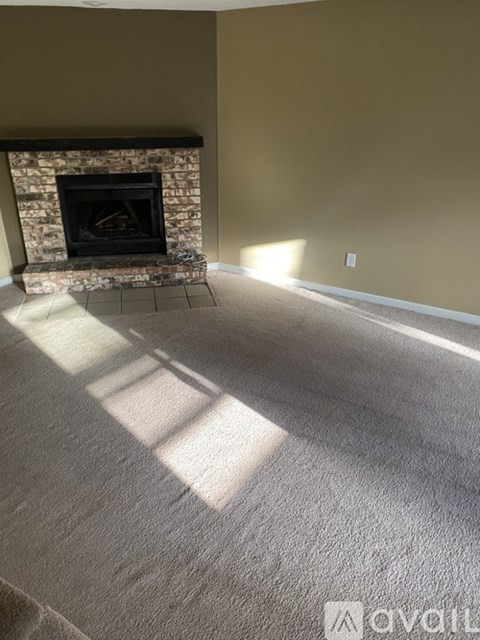 A living room with a fireplace and carpeted floor.
