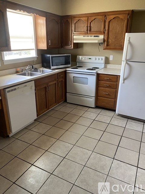 A kitchen with white appliances and brown cabinets.