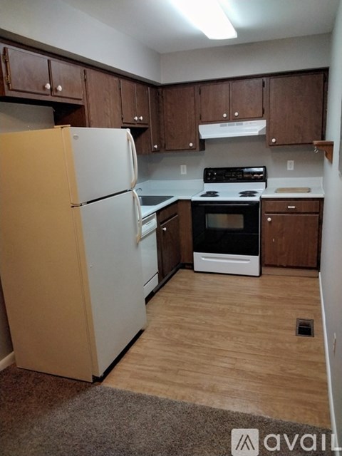 A kitchen with wooden cabinets and a white fridge.
