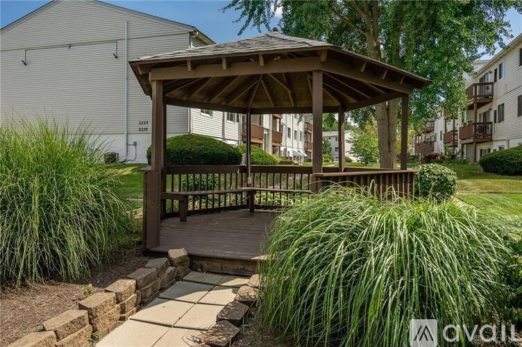 A gazebo is surrounded by grasses and a brick pathway.