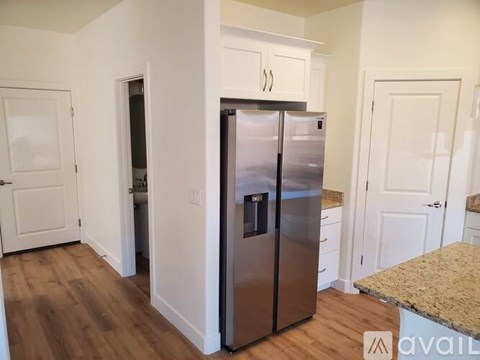 A stainless steel refrigerator in a kitchen with white cabinets.