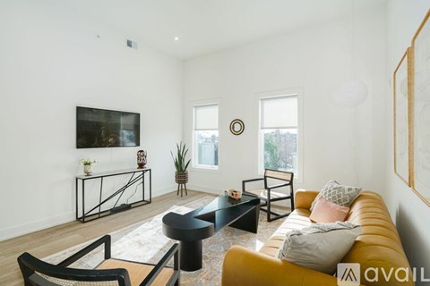 A living room with a yellow couch and a black coffee table.