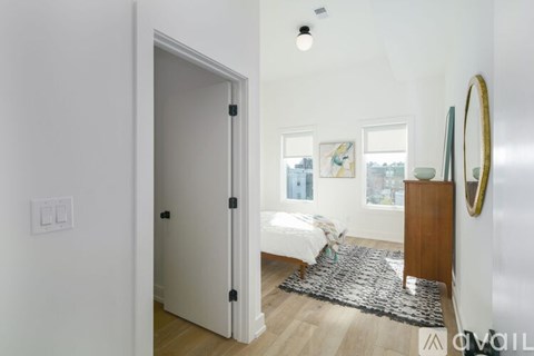A white bedroom with a bed and a mirror on the wall.