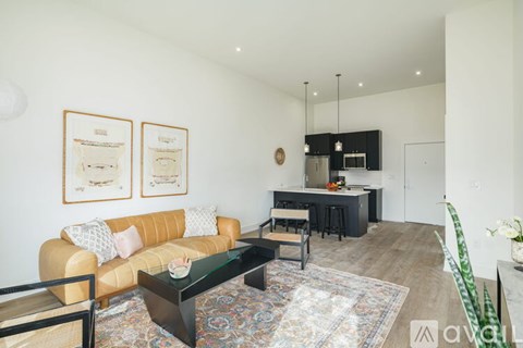 A living room with a tan couch, a black coffee table, and a rug.