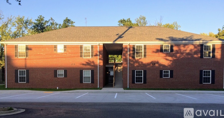 A red brick building with a parking lot in front.