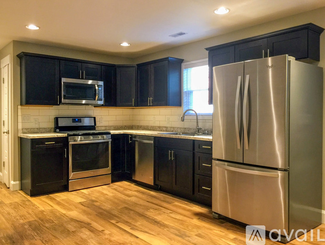 A kitchen with black cabinets and a stainless steel refrigerator.