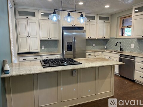 A kitchen with a granite countertop and a stainless steel refrigerator.