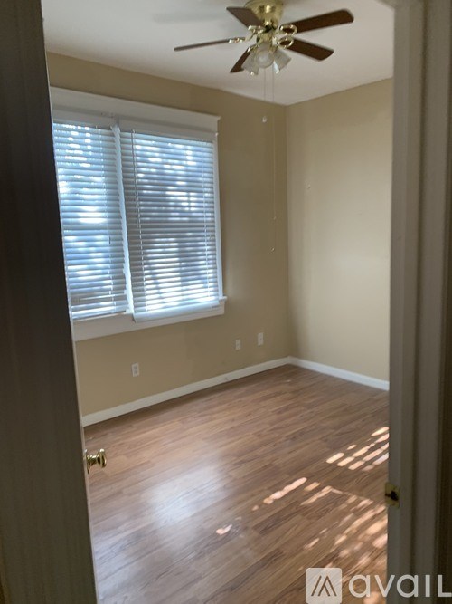 A room with a ceiling fan and a window with blinds.