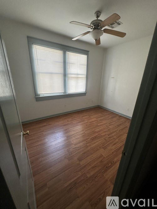 A green house with a white garage door is in front of a tree.