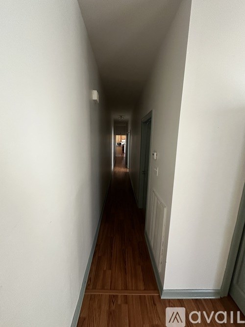 A long hallway with wood floors and white walls.