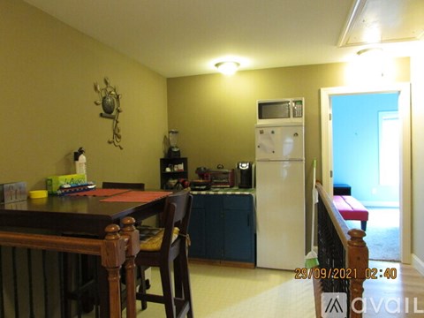 A kitchen with a table and chairs in the foreground and a refrigerator in the background.