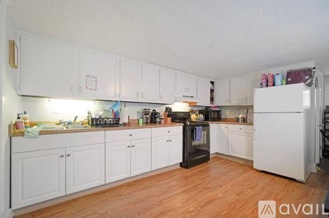 A kitchen with white cabinets and a black fridge.