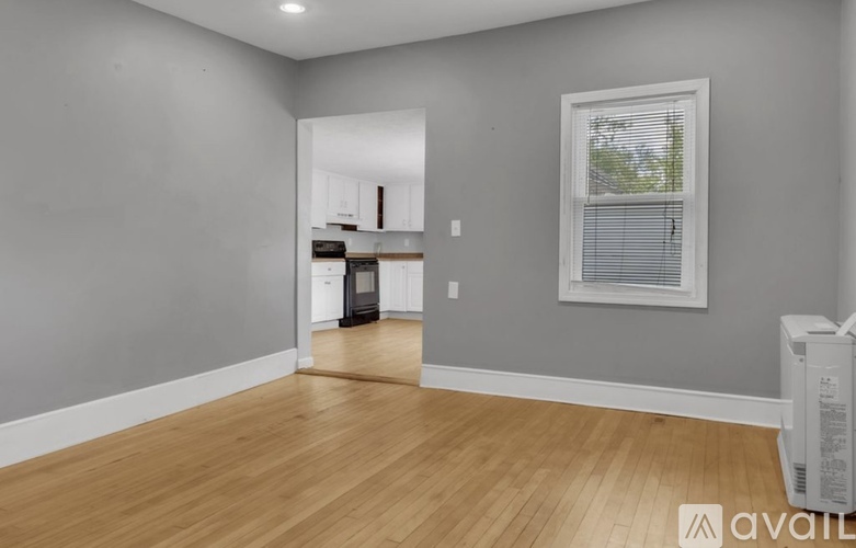 A room with wooden floors and a window with blinds.