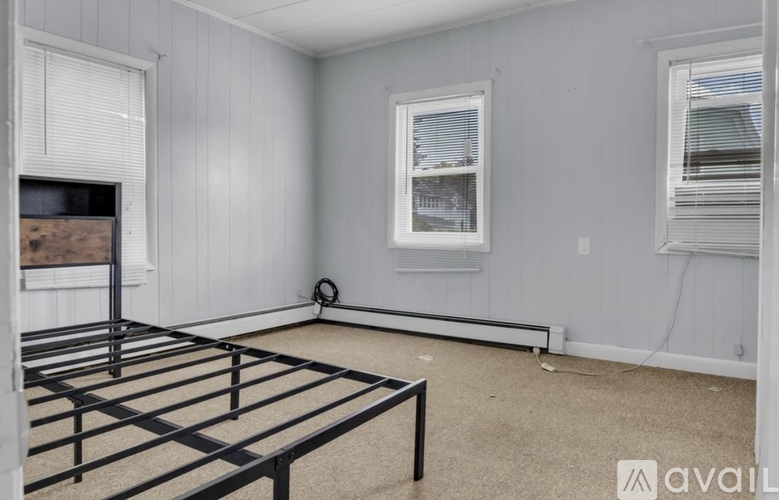 A bedroom with a bed frame and a window with blinds.