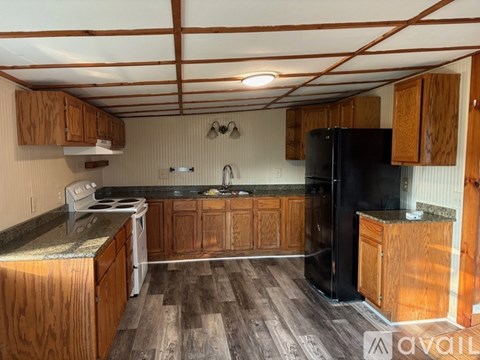 A kitchen with wooden cabinets and a black refrigerator.