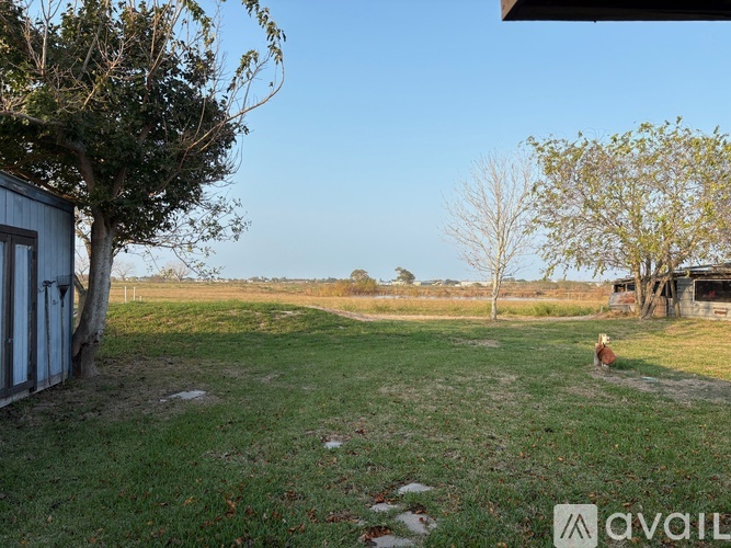 A grassy field with a shed and trees in the background.