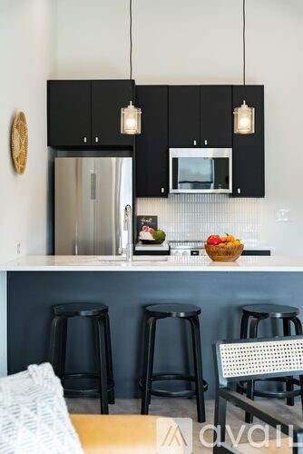 A kitchen with black cabinets and a stainless steel refrigerator.
