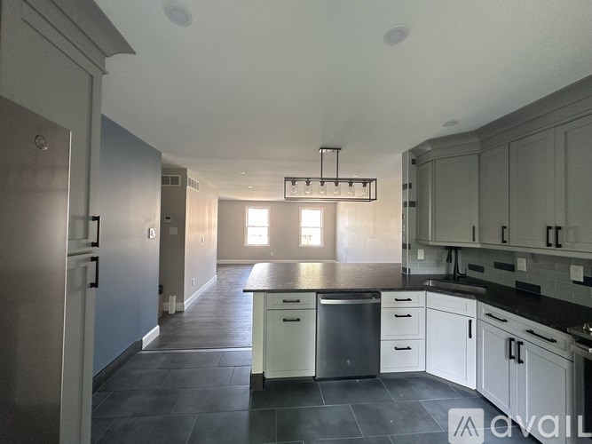 A kitchen with a refrigerator, dishwasher, and cabinets.