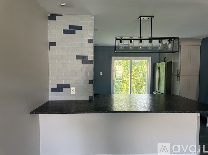 A kitchen with a white island and a black countertop.